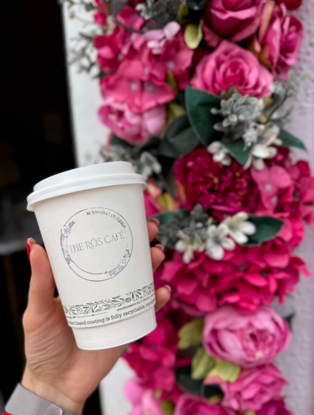 The Rós Café branded coffee cup against the café's signature pink floral wall, Newmarket on Fergus, Co. Clare